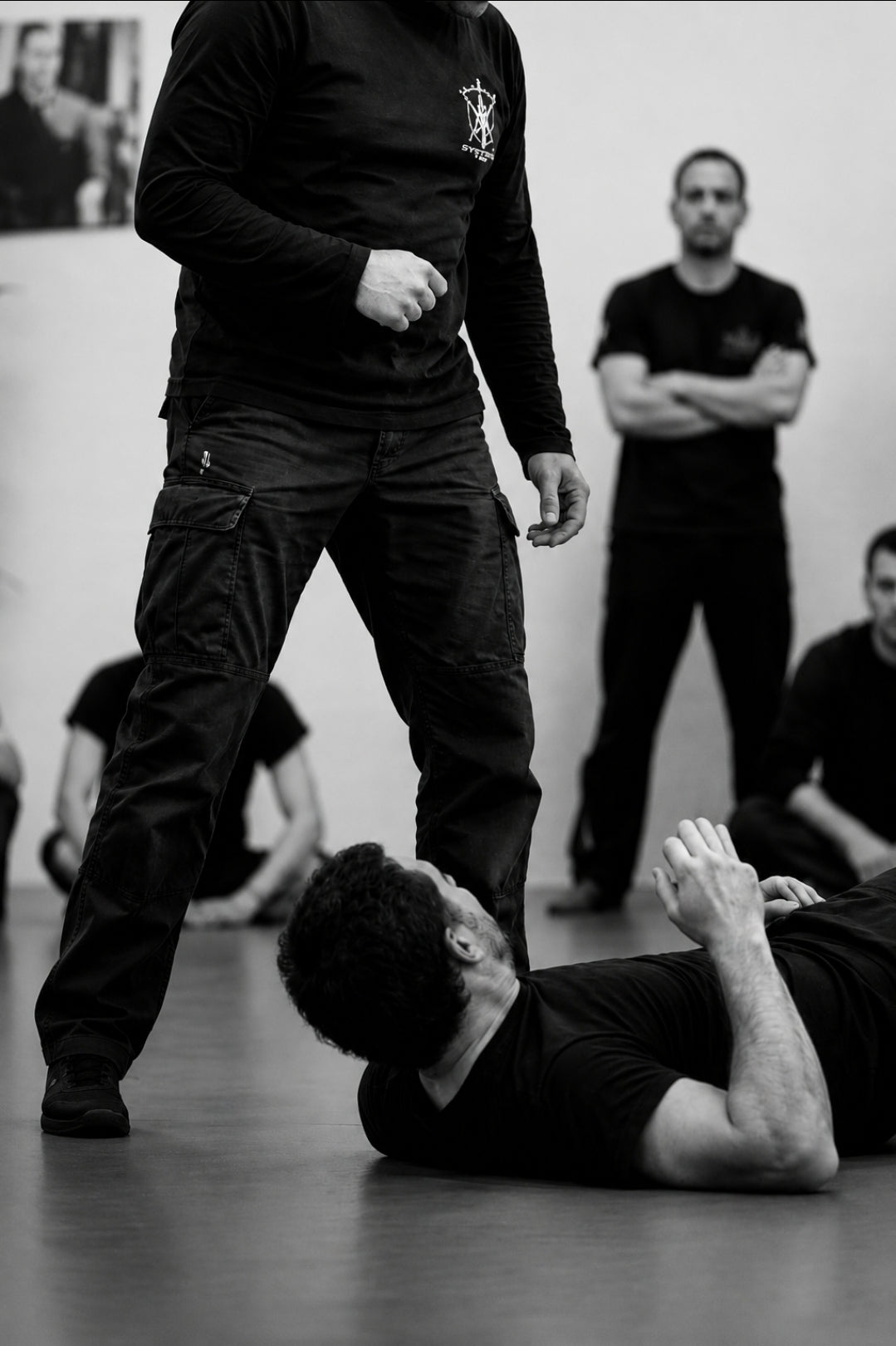 A Systema training demonstration where a student pauses on the ground while an instructor teaches a lesson about adaptation, awareness, and finding another way forward.