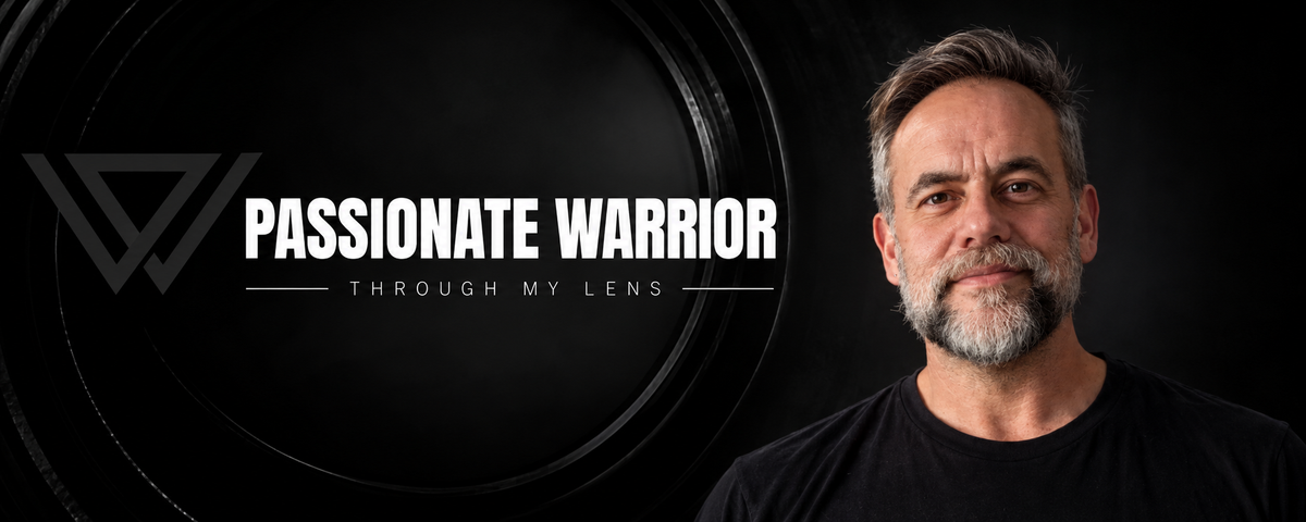 Passionate Warrior – Through My Lens website banner featuring Carlos with salt-and-pepper hair, a gray beard, and a black shirt against a dark background.